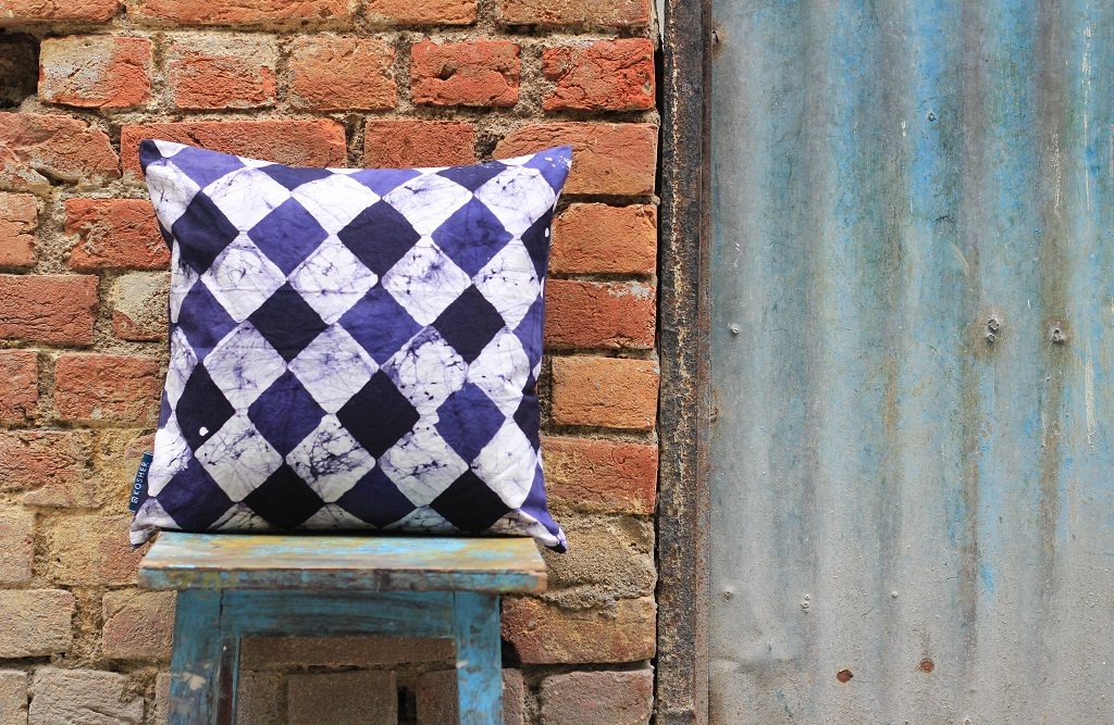 White, purple, and black harlequin throw pillow on a stool
