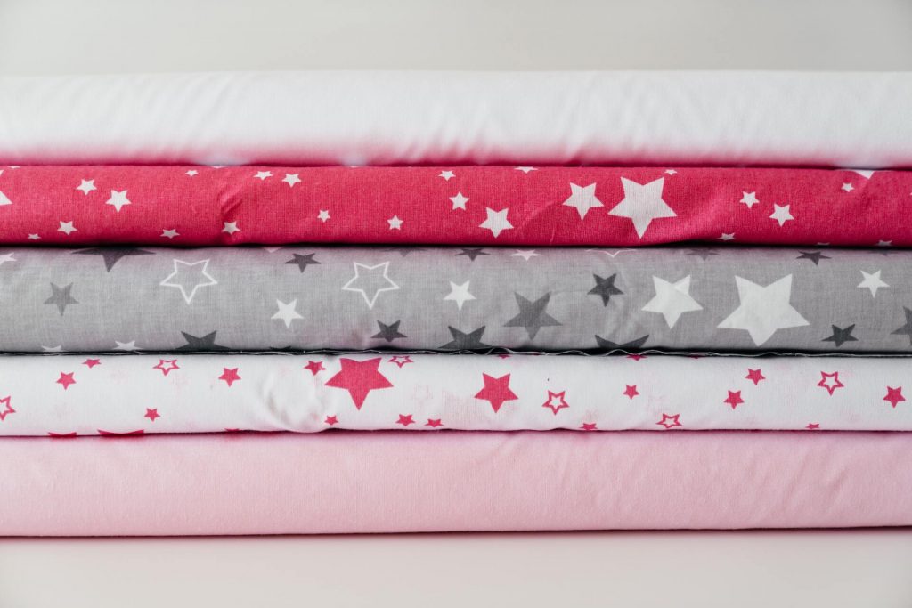 A Pile of Plain and Star Printed Fabric Rolls
