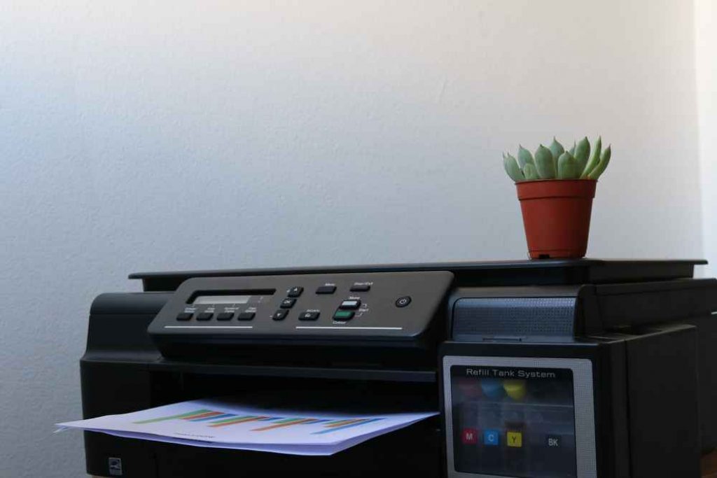 A black colored printer with a plant vase on top
