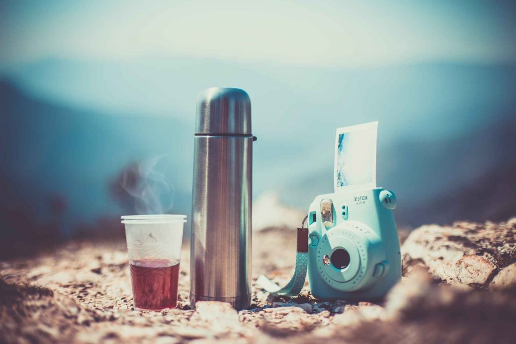 Hydro flask with disposable cup and camera on the rocks